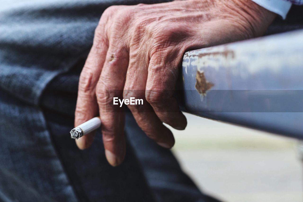 Cropped image of man holding cigarette