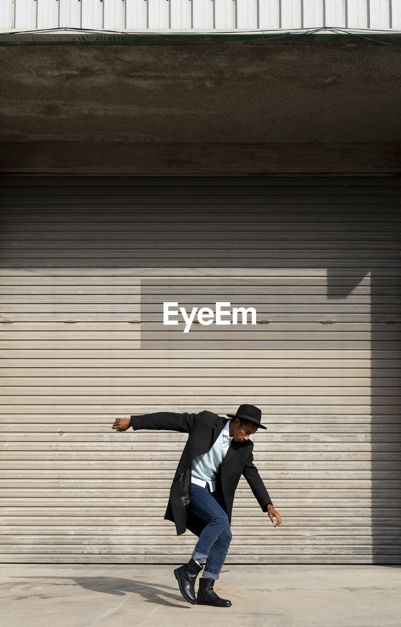 Happy young man dancing against shutter