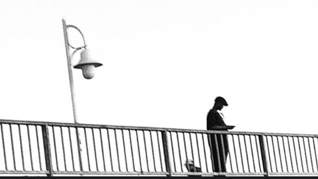 LOW ANGLE VIEW OF WOMAN STANDING ON RAILING