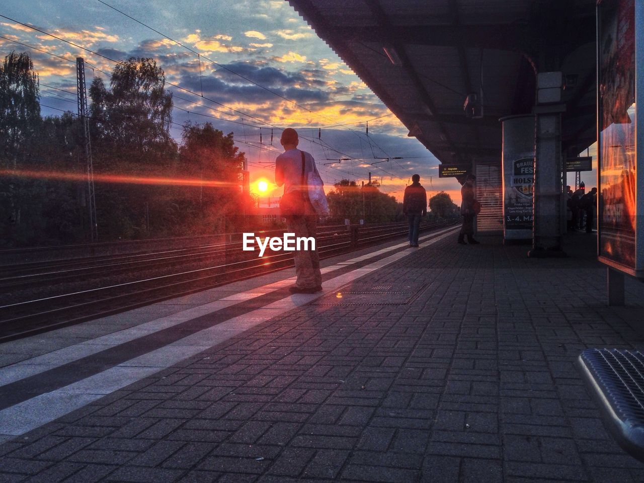 People at railway station during sunset