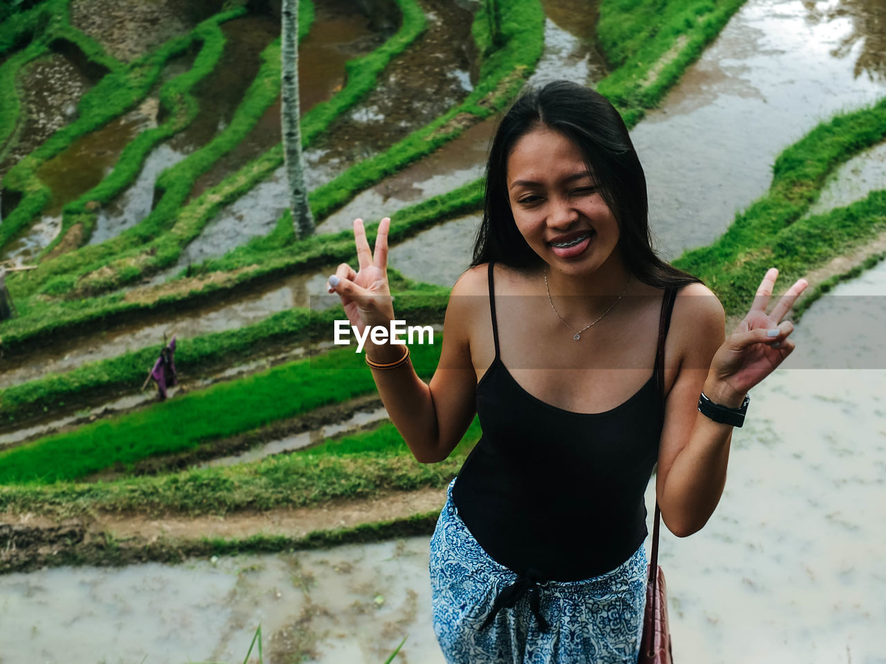 Beautiful young woman standing against rice paddy 