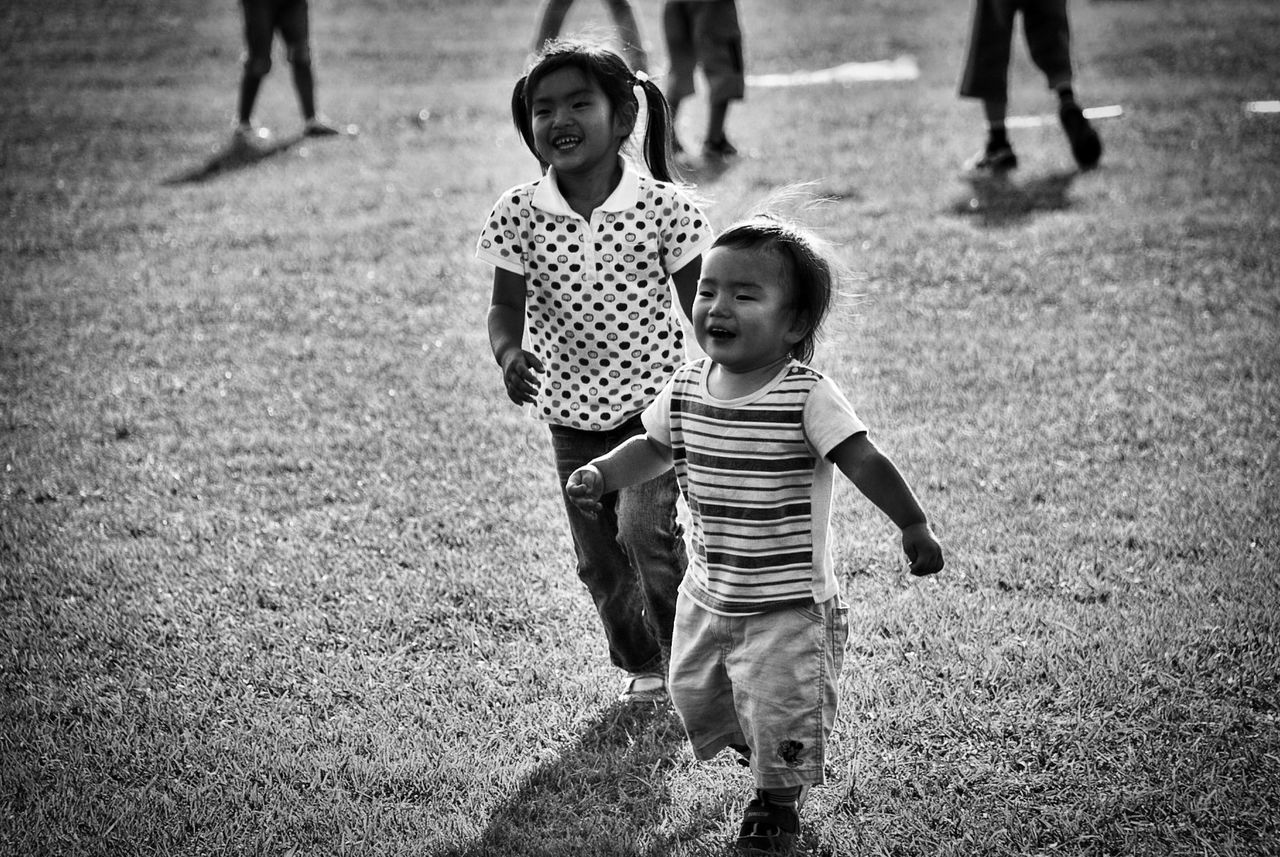 Full length of happy siblings on grassy field