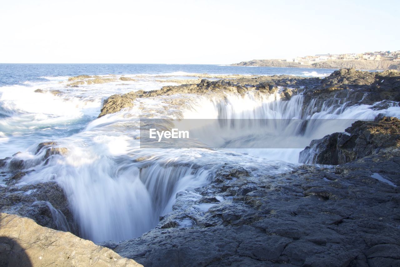 Scenic view of waterfall against sky