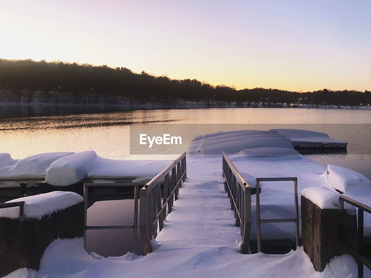 SCENIC VIEW OF SNOW COVERED LAKE AGAINST SKY AT SUNSET