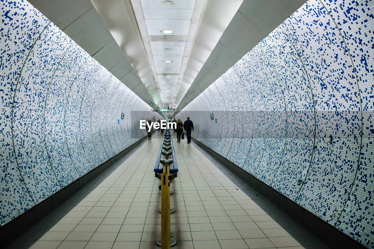 Rear view of people walking in underground walkway