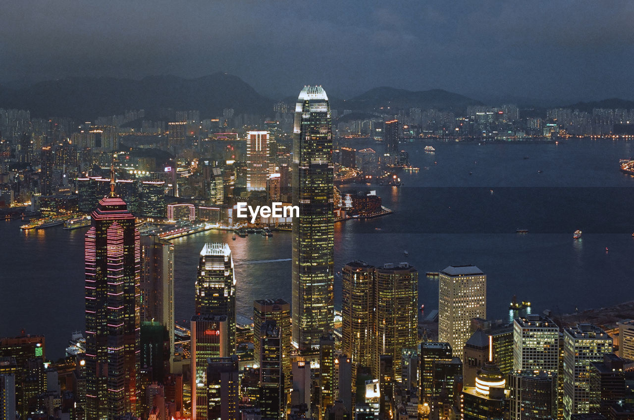 Illuminated modern buildings in city against sky at night