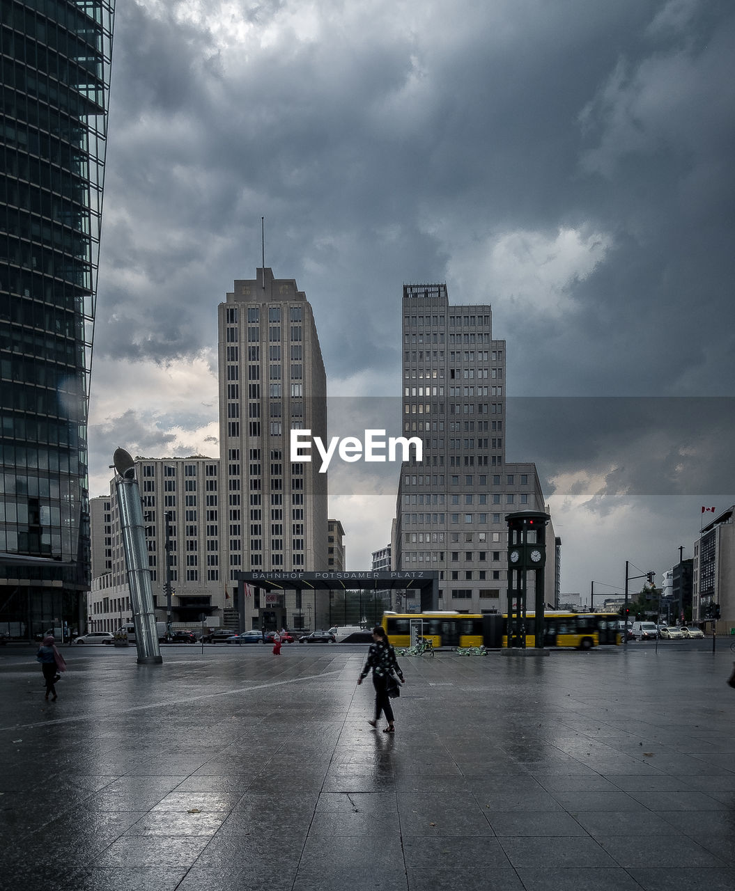 PEOPLE ON WET STREET AGAINST BUILDINGS IN CITY