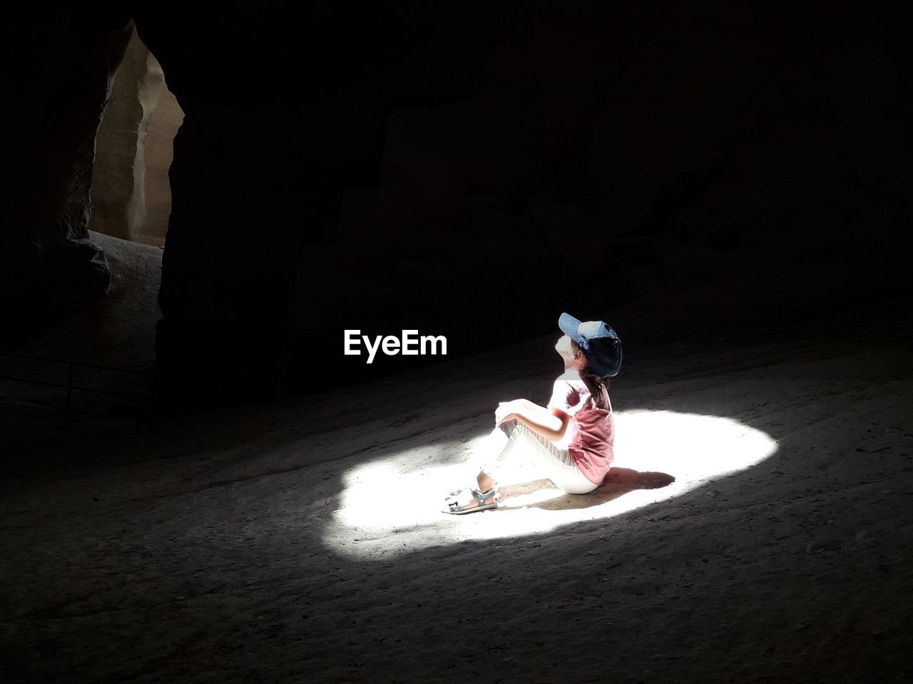 High angle view of sunlight falling on boy sitting in caves