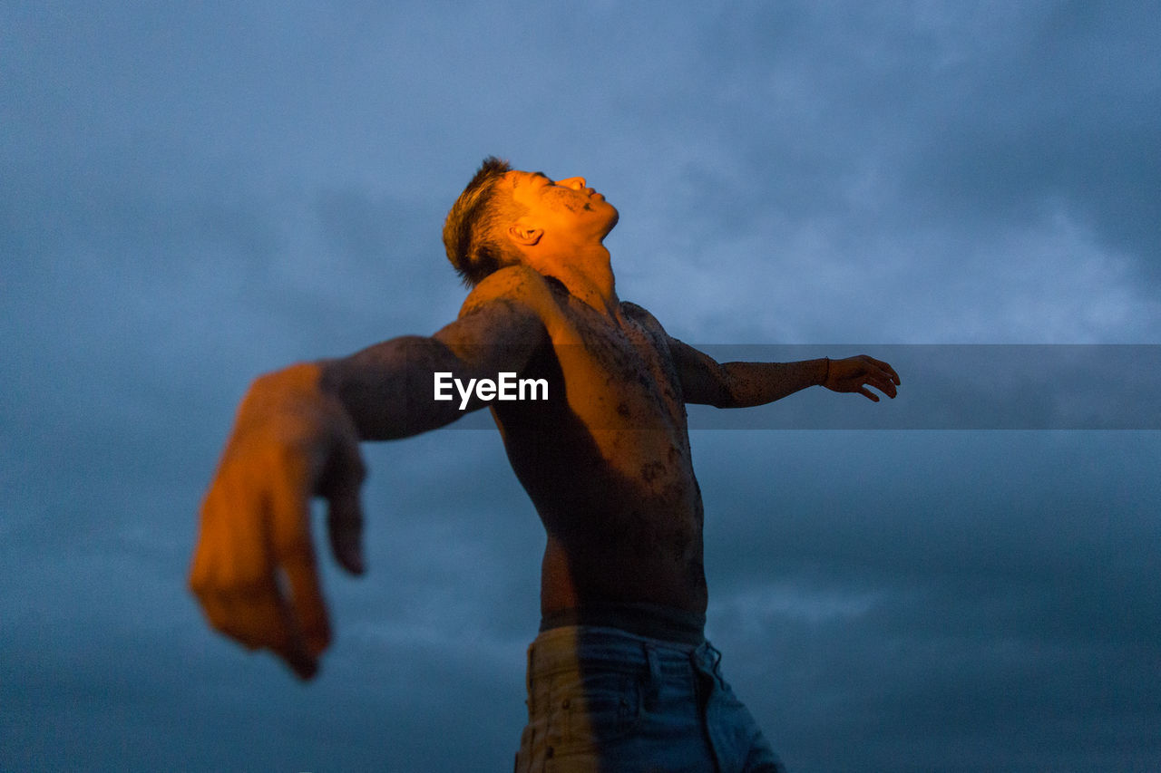 Low angle view of shirtless man against sky