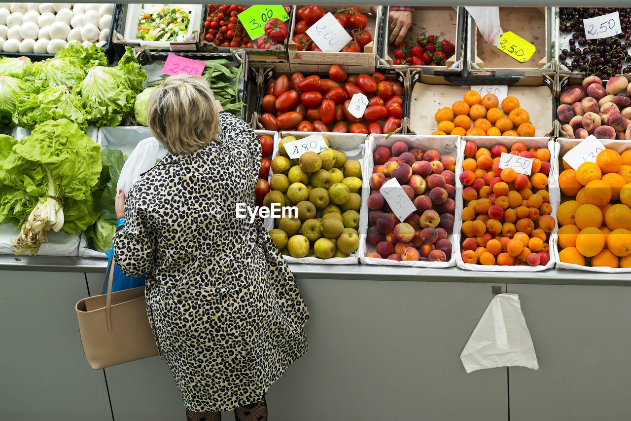 High angle view of woman buying vegetables at market stall