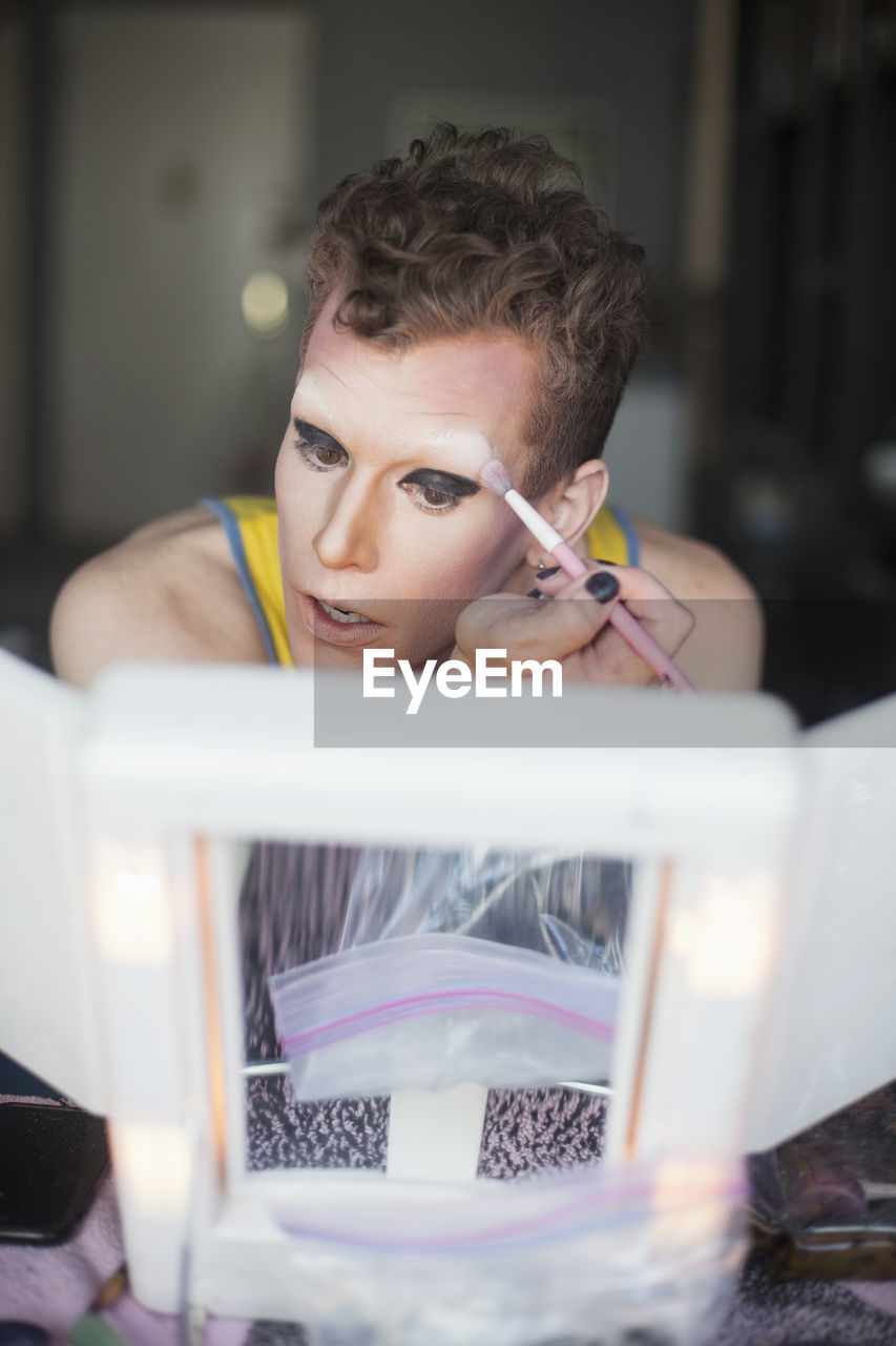 Young man applying drag makeup