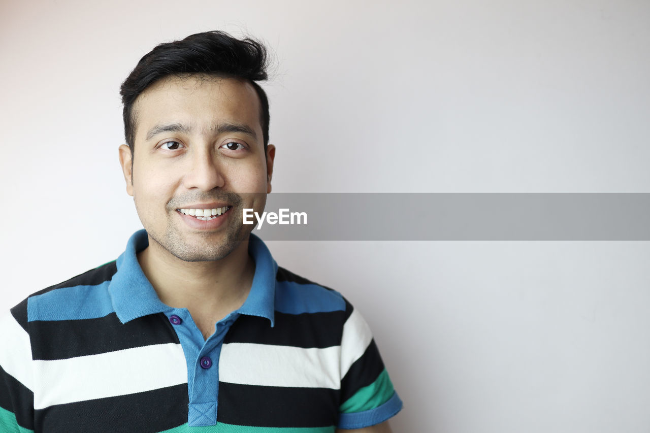 PORTRAIT OF SMILING MAN AGAINST WALL