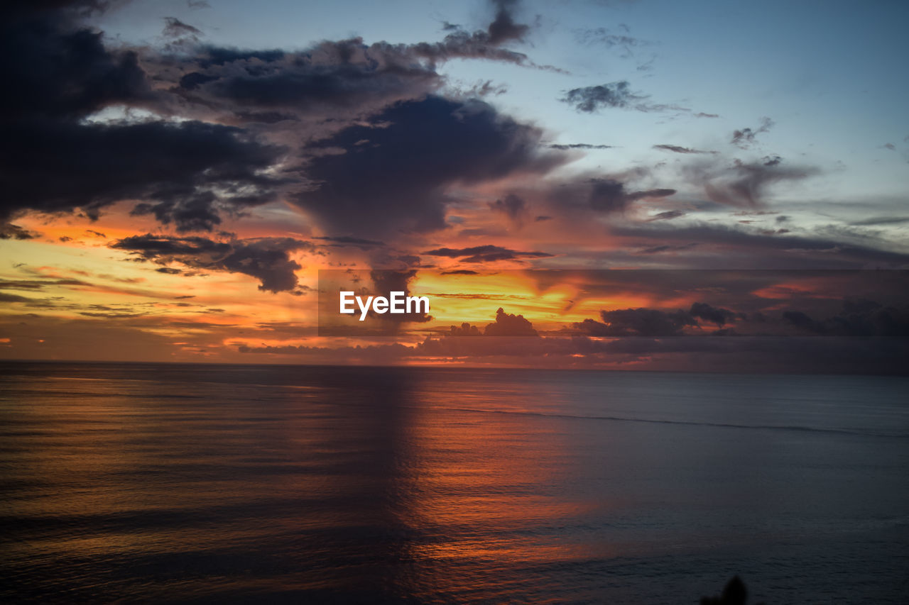 Scenic view of sea against dramatic sky during sunset