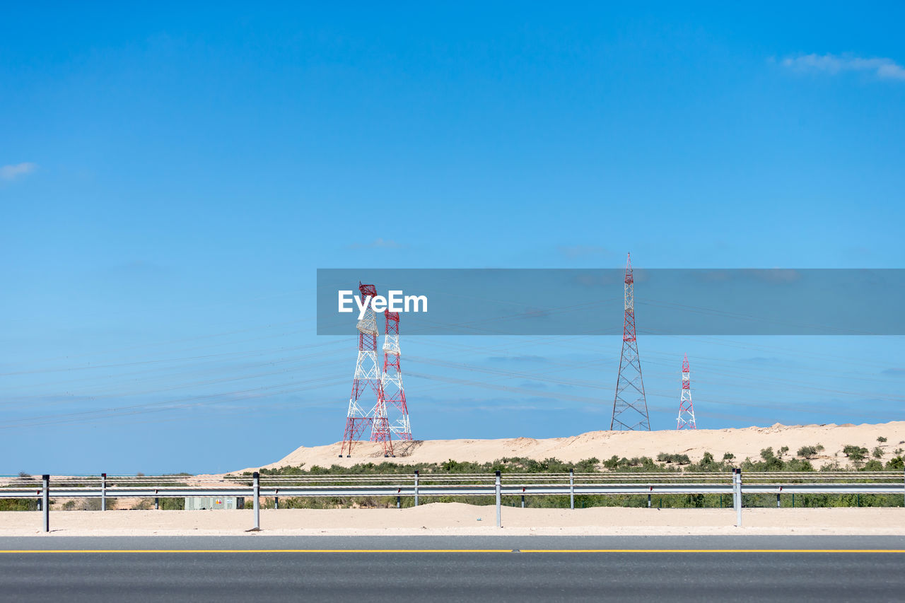 TOWER AGAINST SKY WITH FACTORY IN BACKGROUND