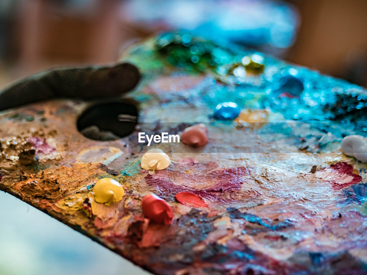 Cropped hand of painter holding colorful paints in palette