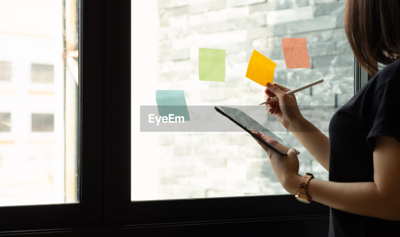 MIDSECTION OF WOMAN WORKING AT WINDOW