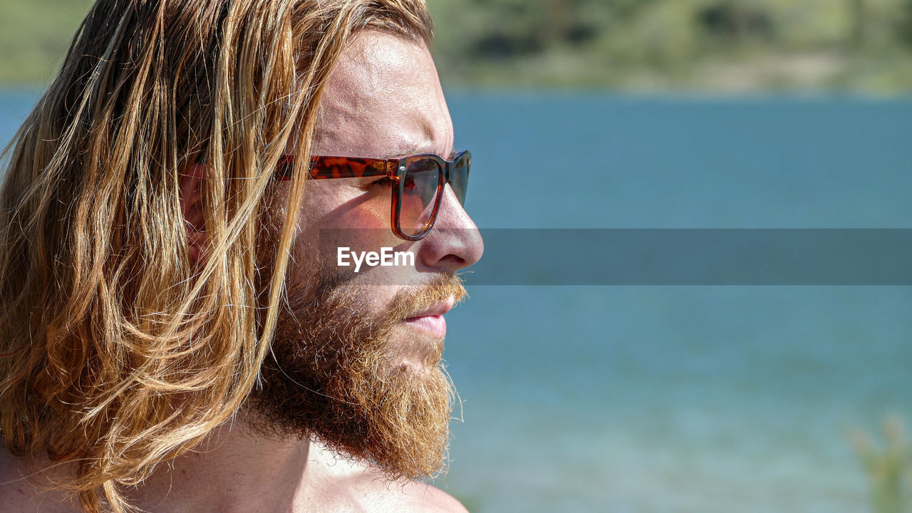 Close-up of man wearing sunglasses standing by lake