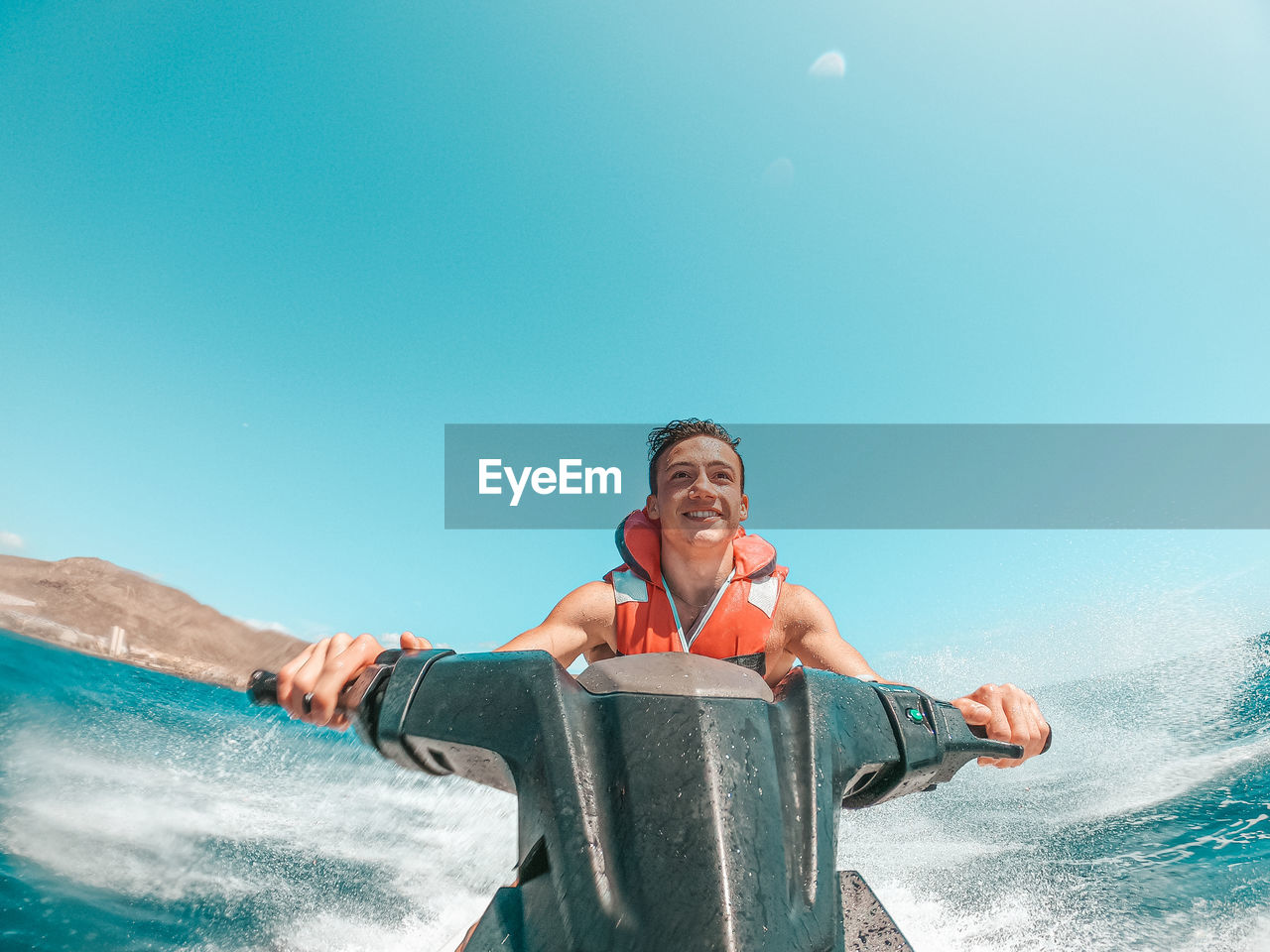 Smiling teenager driving jet ski in sea