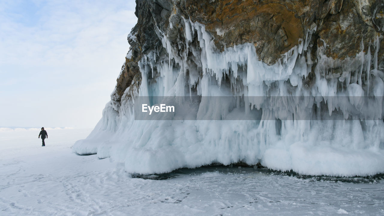 PANORAMIC SHOT OF PERSON STANDING ON FROZEN SEA