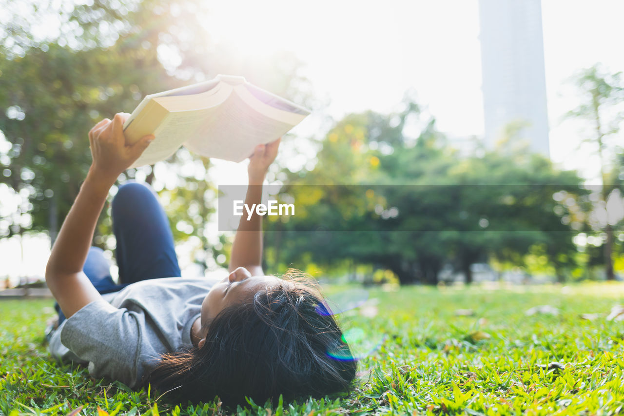 REAR VIEW OF WOMAN LYING ON GRASS IN PARK