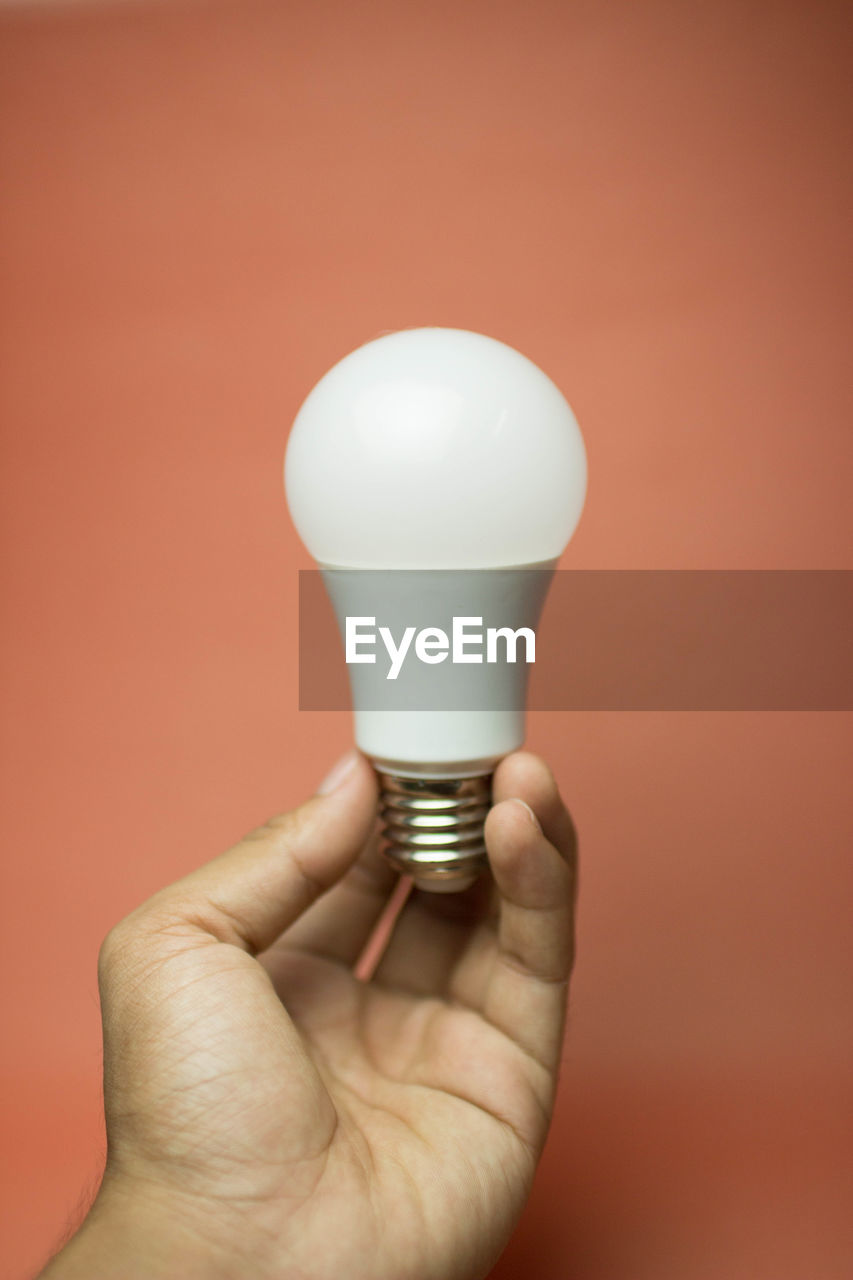 CLOSE-UP OF HUMAN HAND HOLDING LIGHT BULB