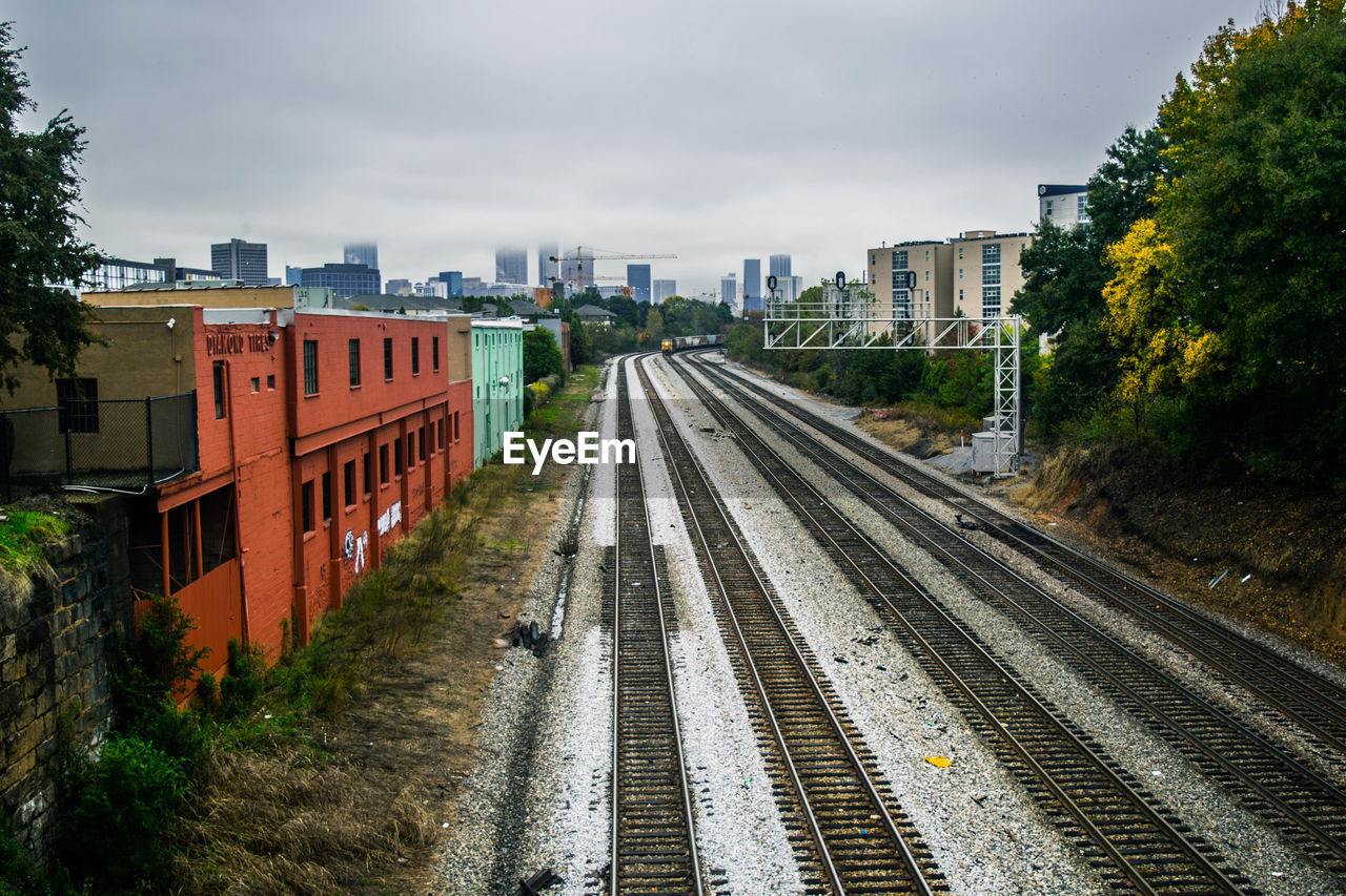 HIGH ANGLE VIEW OF RAILROAD TRACKS BY BUILDINGS IN CITY