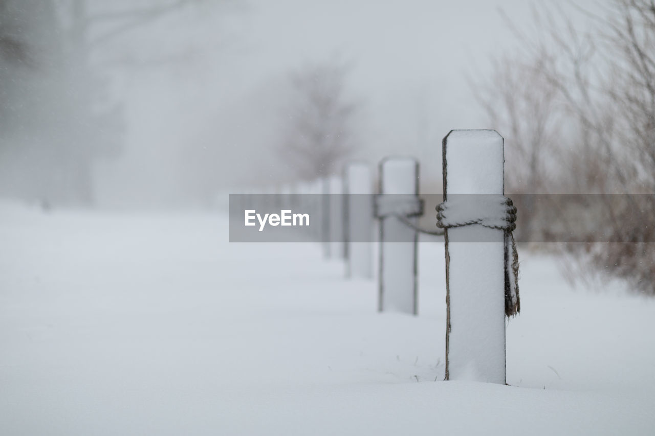 SNOW COVERED WOODEN POSTS ON FIELD