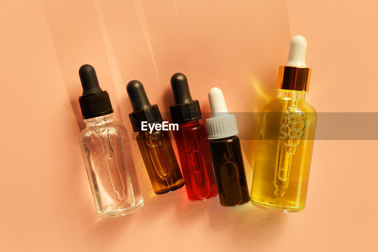 bottle, container, hand, cosmetics, nail, finger, indoors, glass bottle, beauty product, group of objects, food and drink, studio shot, nail polish, yellow, make-up, still life, variation, close-up