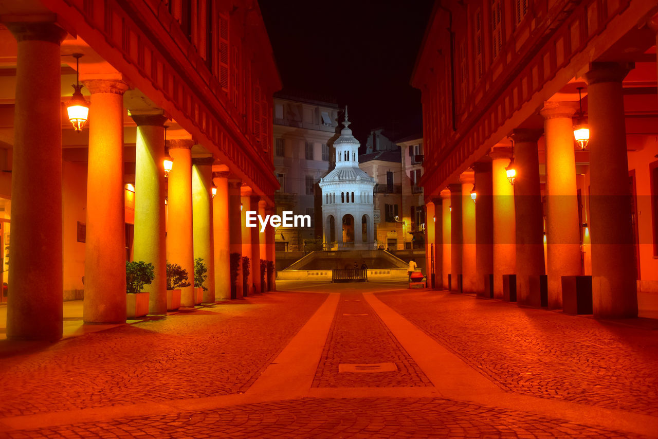 ILLUMINATED ALLEY AMIDST BUILDINGS IN CITY