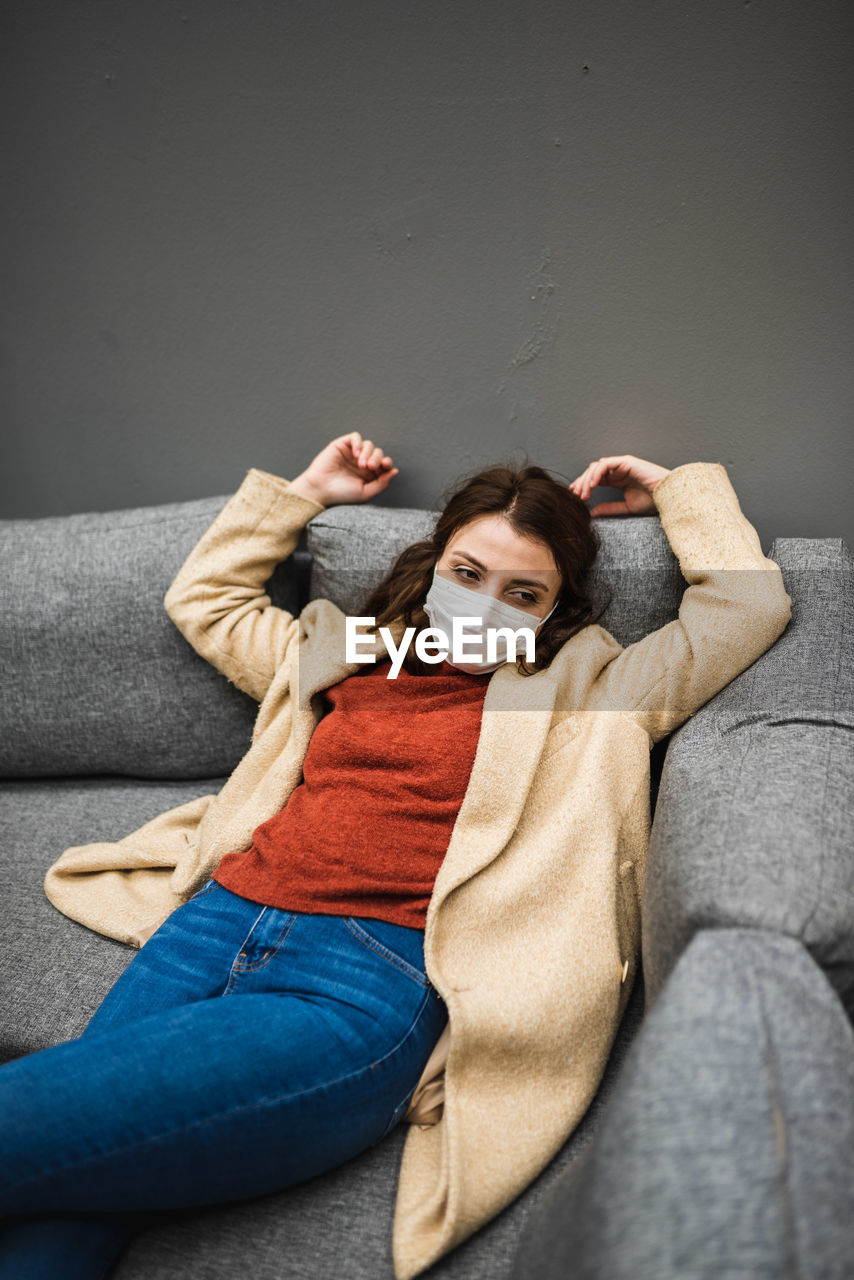High angle view of woman wearing mask lying down on sofa