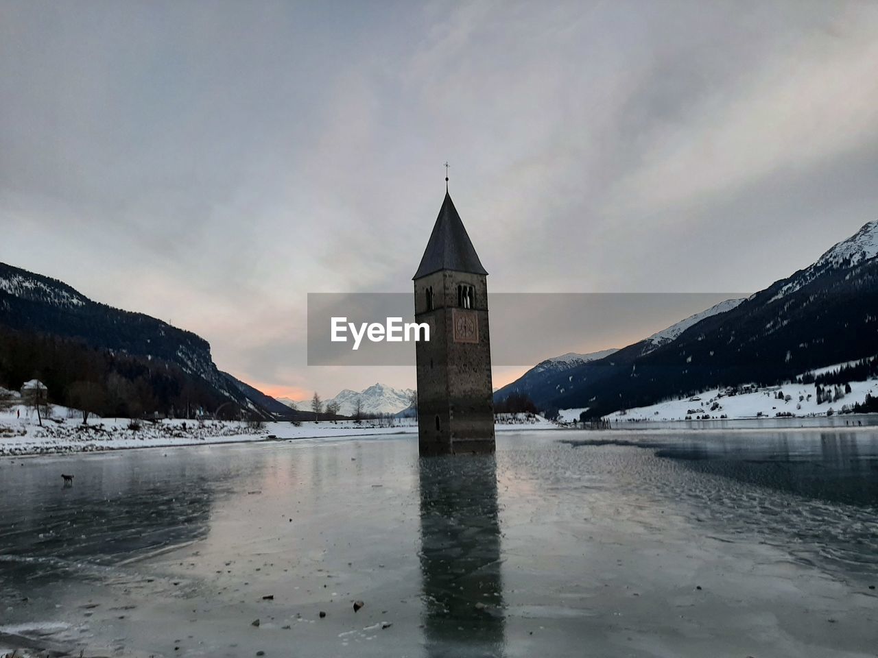 TOWER BY BUILDING AGAINST SKY DURING WINTER