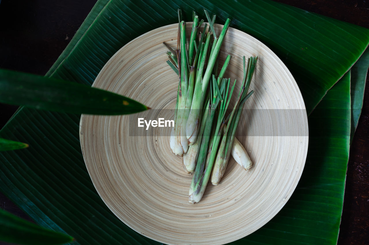 Fresh lemongrass cymbopogon citratus or citronella, serai on a wooden plate.