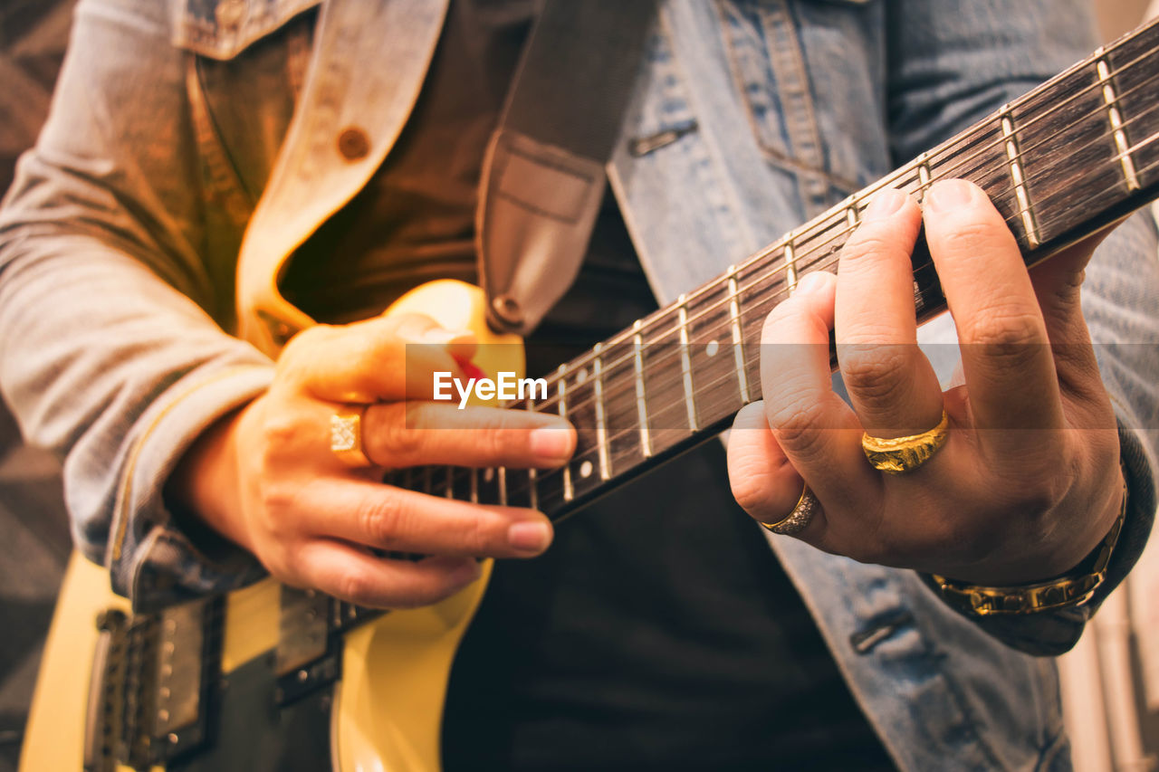 Midsection of man playing guitar