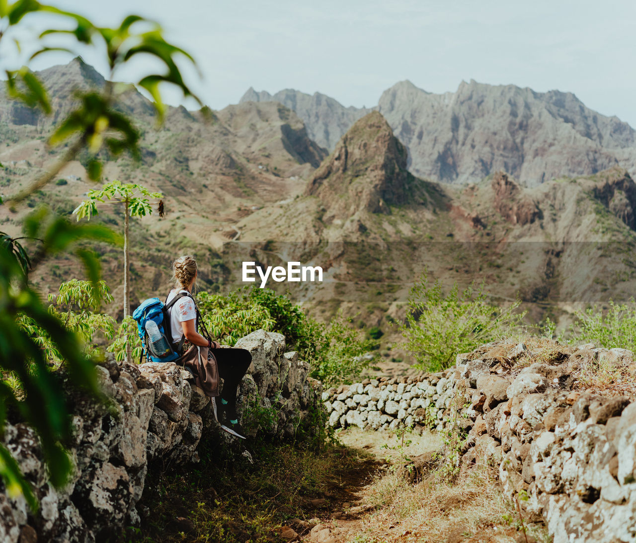 Woman sitting on rock against mountains