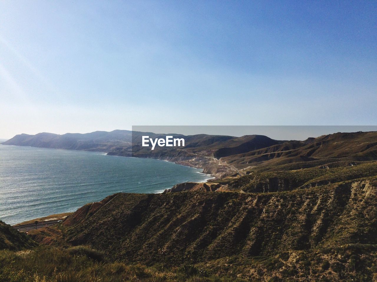 Scenic view of sea and mountains against clear sky