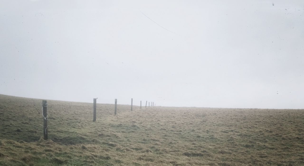 Scenic view of landscape against clear sky during foggy weather