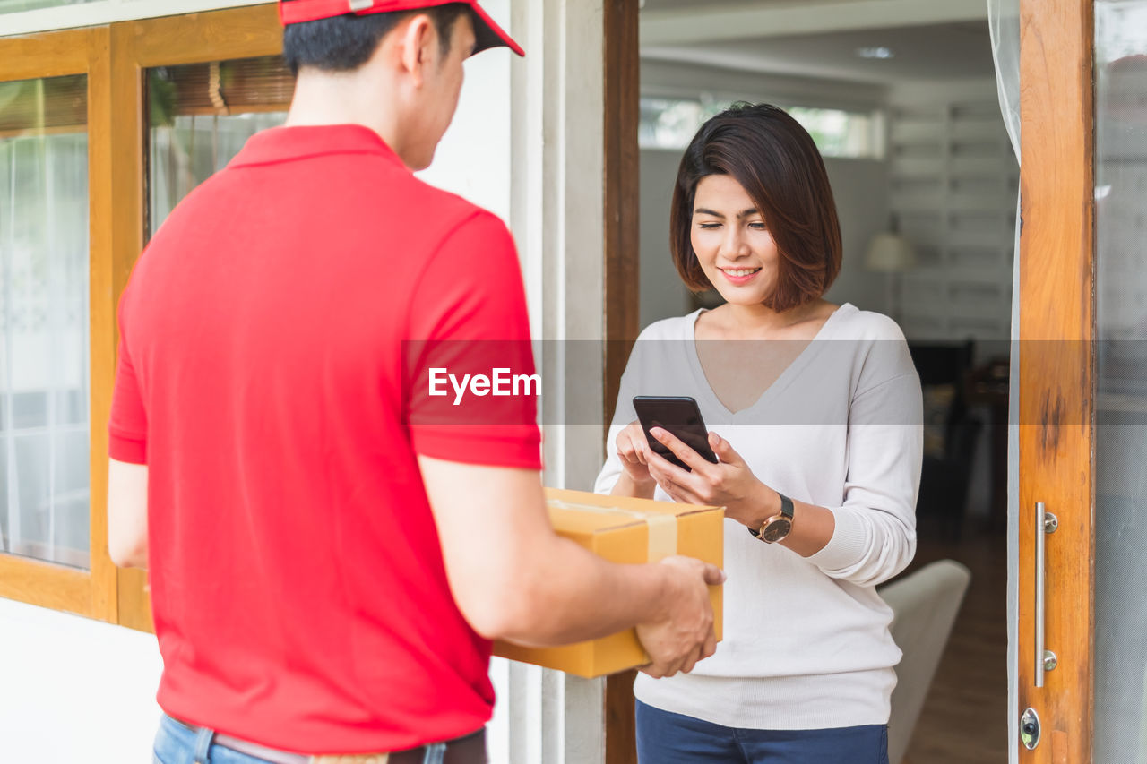 Delivery person giving parcel to customer standing outdoors