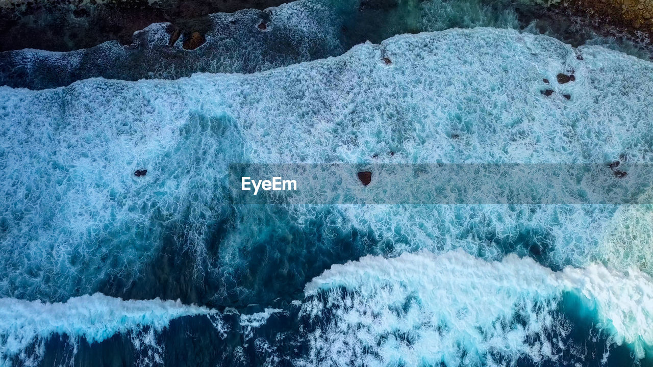 Texture dark ocean waves with white foam. drone filming breaking surf in indian ocean, nusa penida