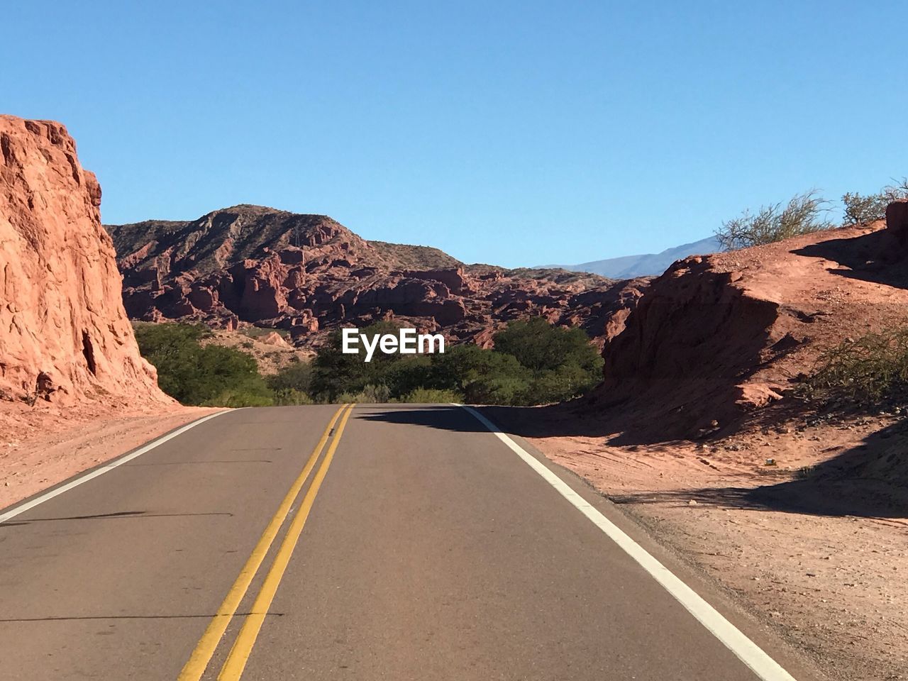 ROAD BY MOUNTAINS AGAINST CLEAR SKY