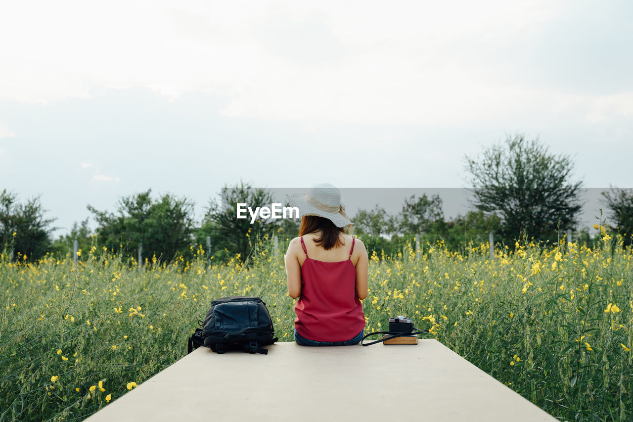 WOMAN STANDING ON FIELD AGAINST SKY