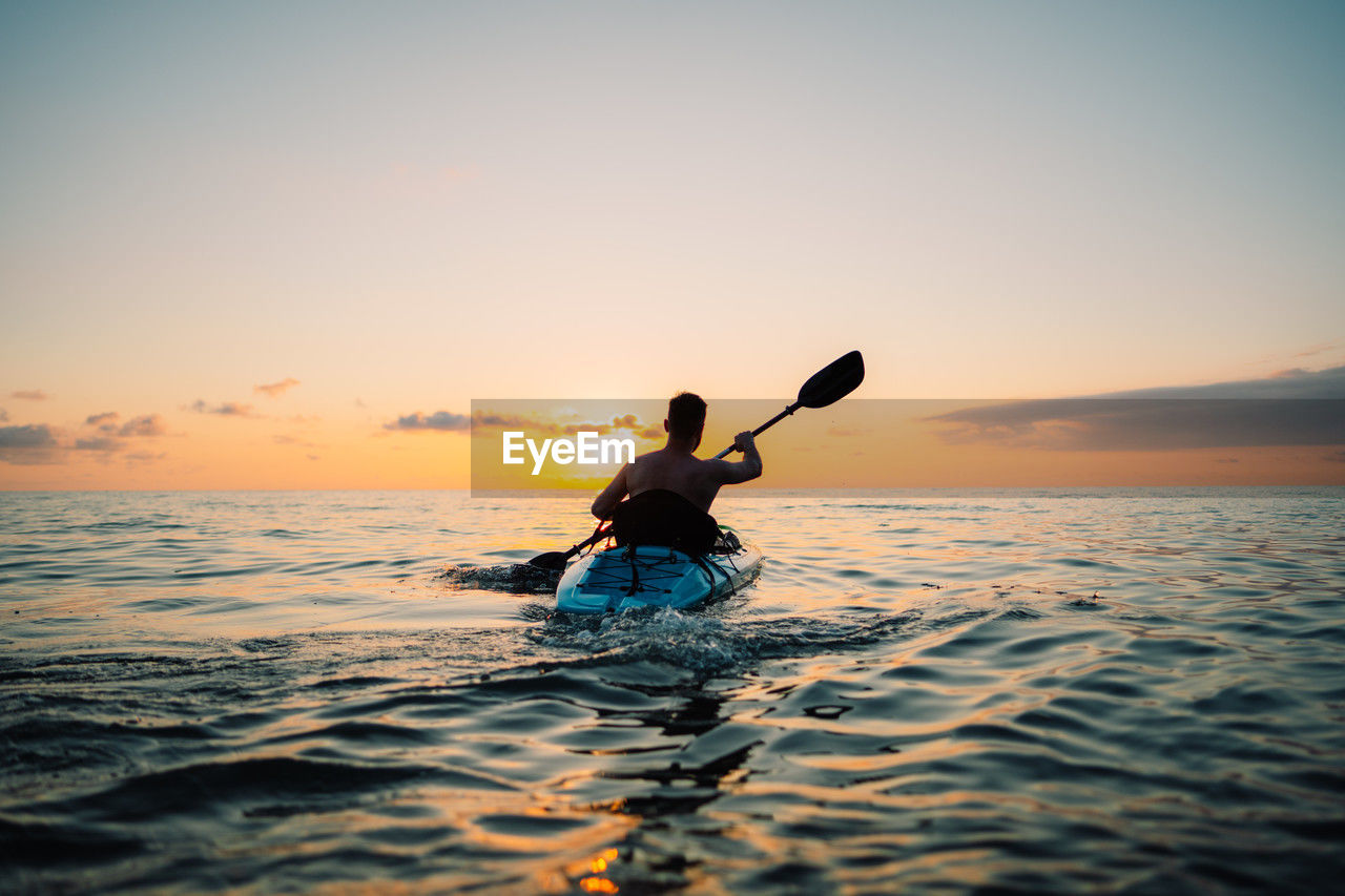 A man is sailing on a sup board at sunset on the sea. high quality photo