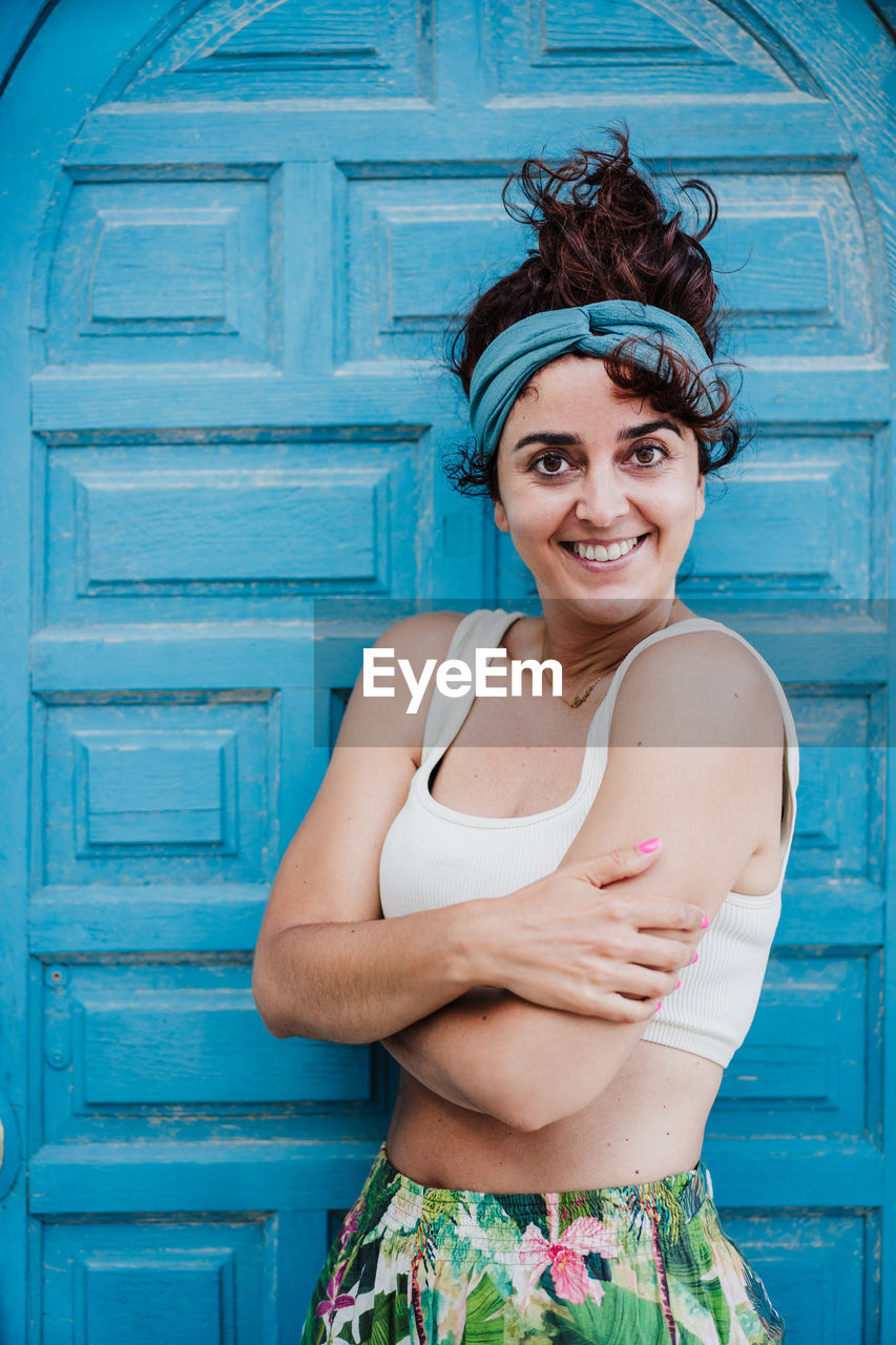 Portrait of smiling young woman standing against wall