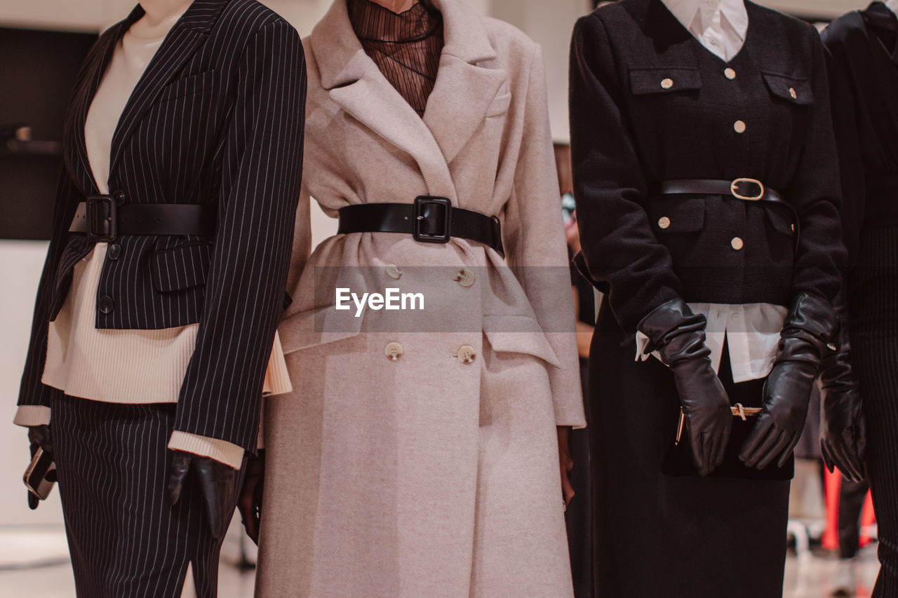 Fashionable details of a black classic outfits and a warm belted long beige coat.