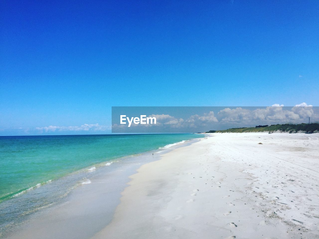 Scenic view of beach against blue sky