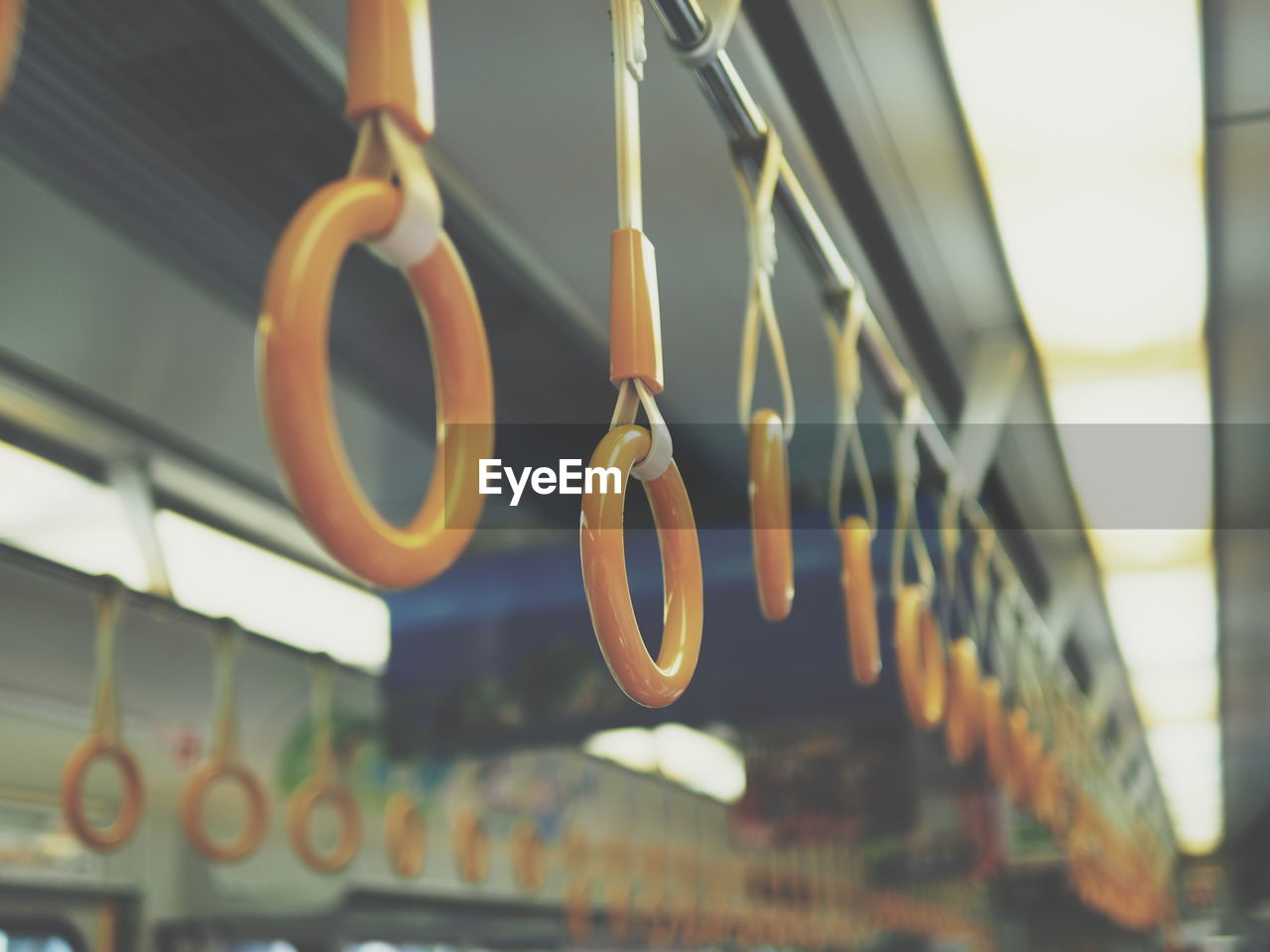 Close-up of handles hanging in illuminated bus