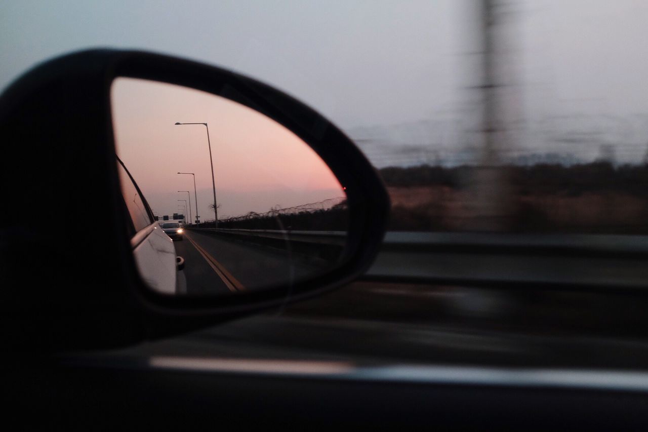 Cropped image of car mirror against sky during sunset