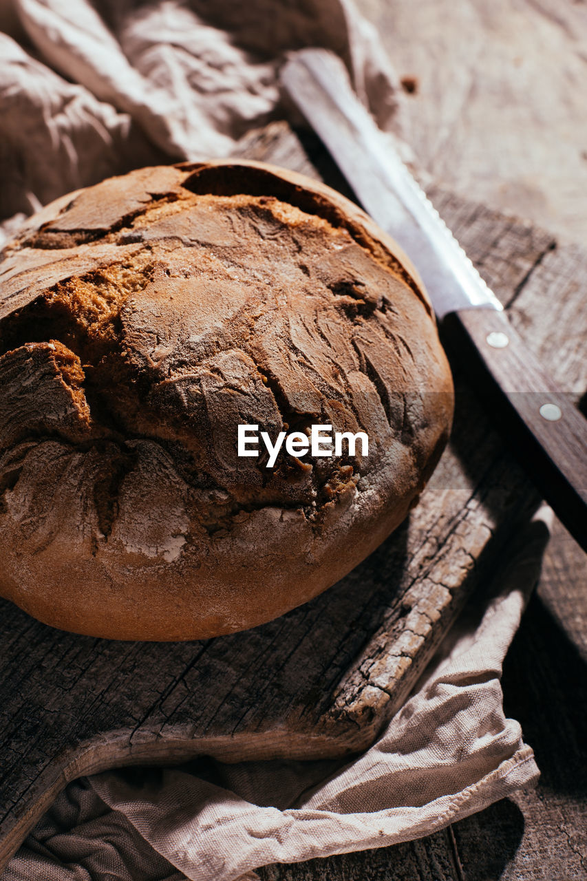 From above of delicious freshly baked bread placed on aged cutting board on wooden table in kitchen