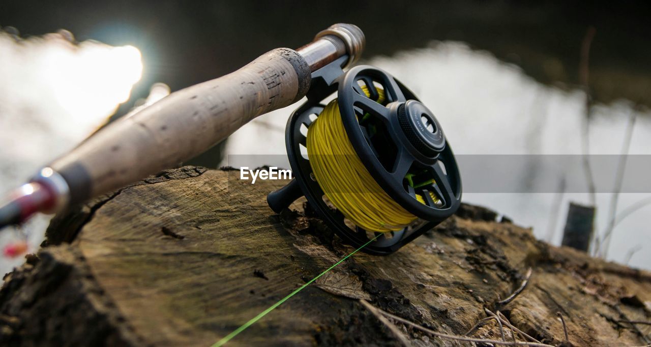 Close-up of fishing rod and spool on tree stump
