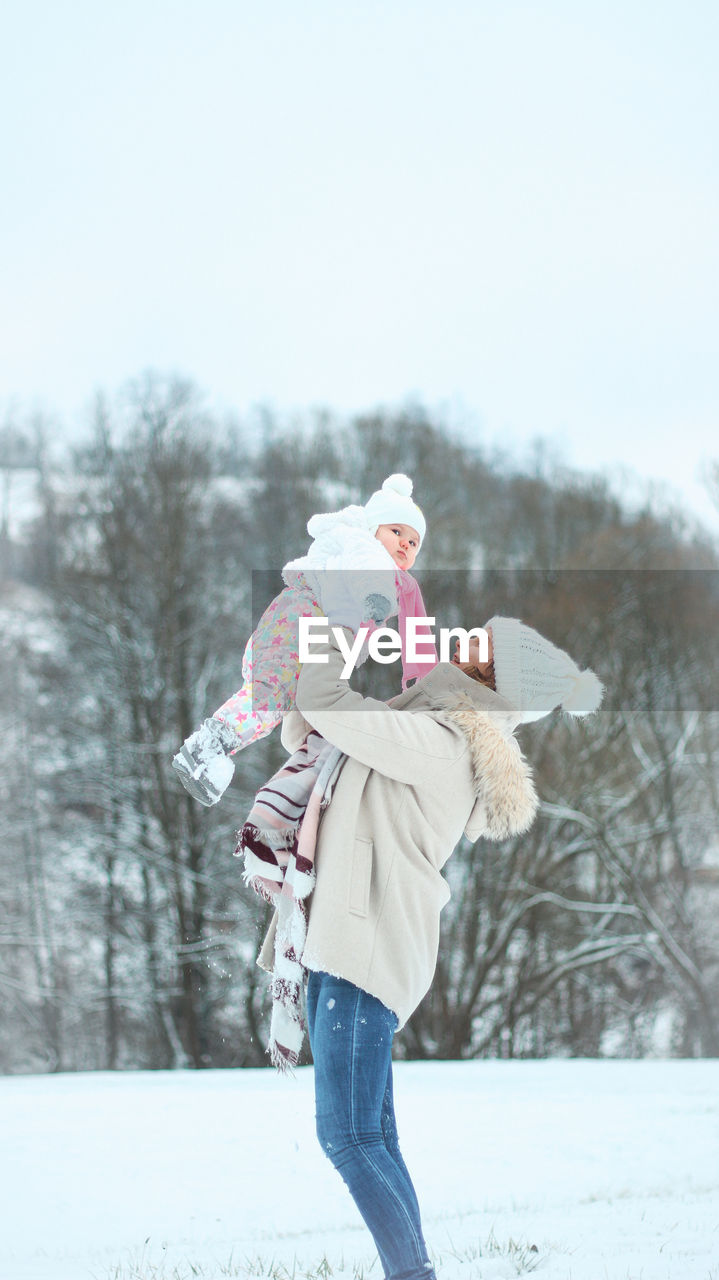 Woman standing on snow field against trees during winter