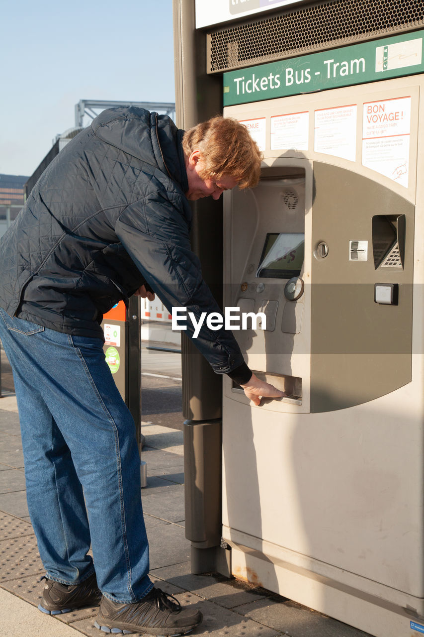 SIDE VIEW OF MAN STANDING ON MACHINE